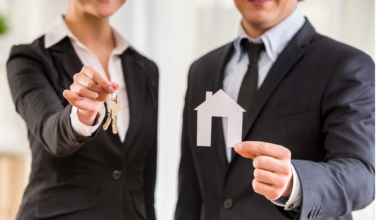 Two people in business suits are holding objects toward the camera; one holds a set of house keys and the other holds a paper cutout of a house, symbolizing real estate or home ownership. Their faces are partially out of frame.