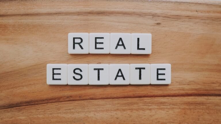 White letter tiles on a wooden surface spell out REAL ESTATE in two rows, representing the dynamic market of multifamily real estate sale in California.